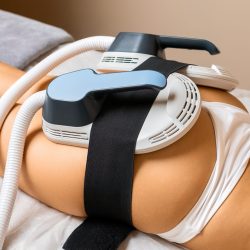 For precise body sculpting, dedicated equipment is positioned on the buttocks of a young woman.